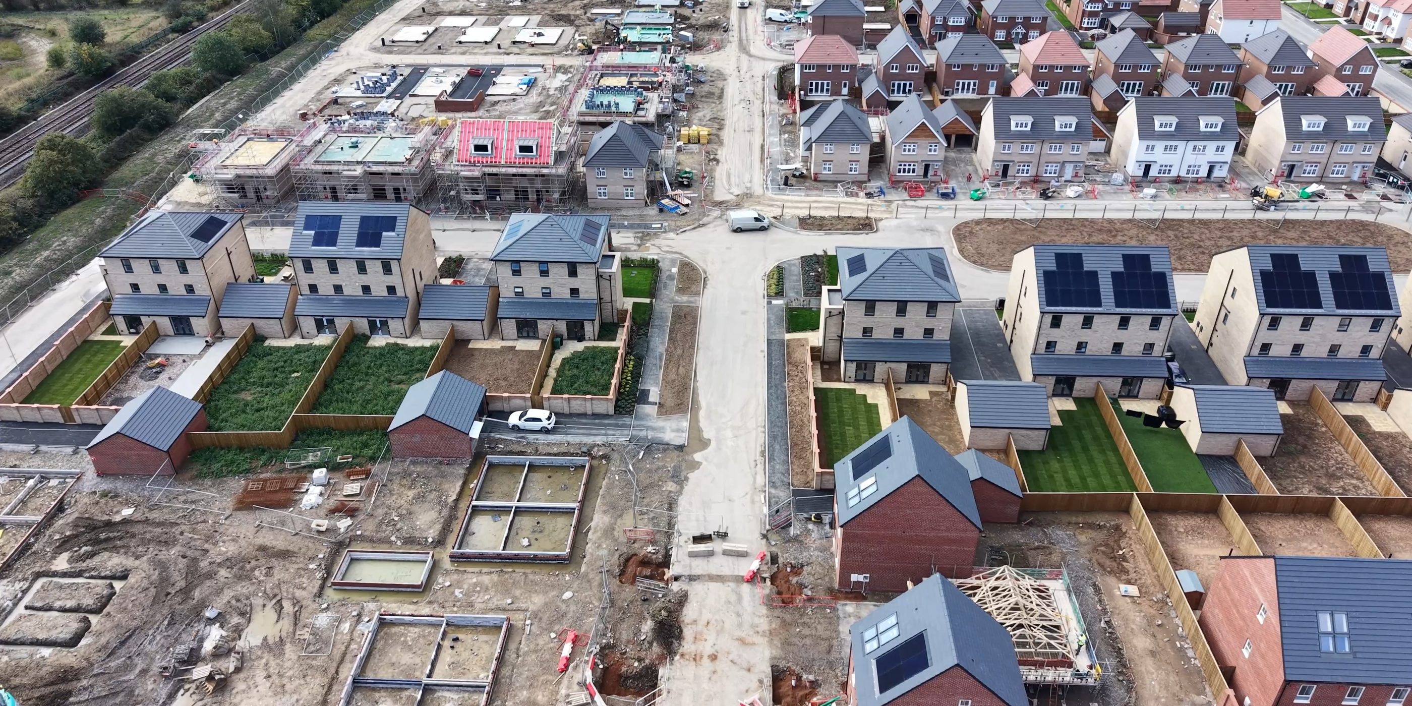 Luchtfoto van een nieuwbouwwijk in aanbouw, met woningen in verschillende stadia van afbouw